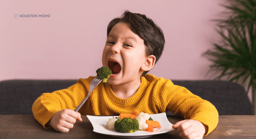 child eating a plate of vegetables