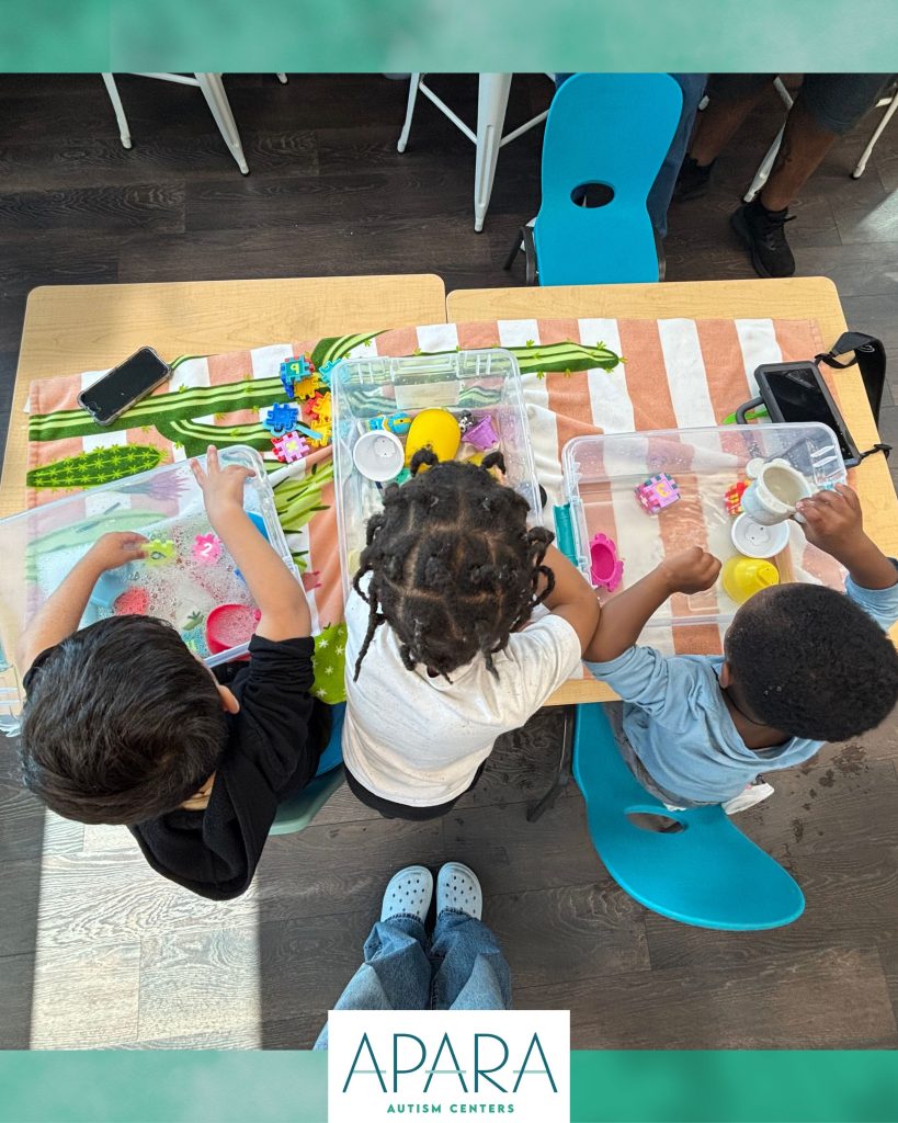 children sitting at table with sensory bins
