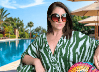woman in caftan sits in front of resort pool