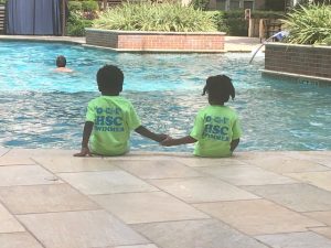 twins sitting on edge of a pool