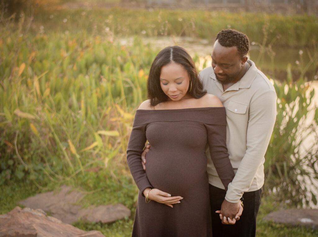 A couple stand in a field, the woman is pregnant