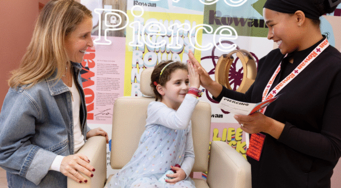 girl getting her ears pierced high fives the piercer while her mom watches, smiling