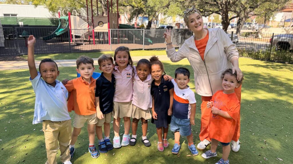 Preschool kids stand with teacher outside