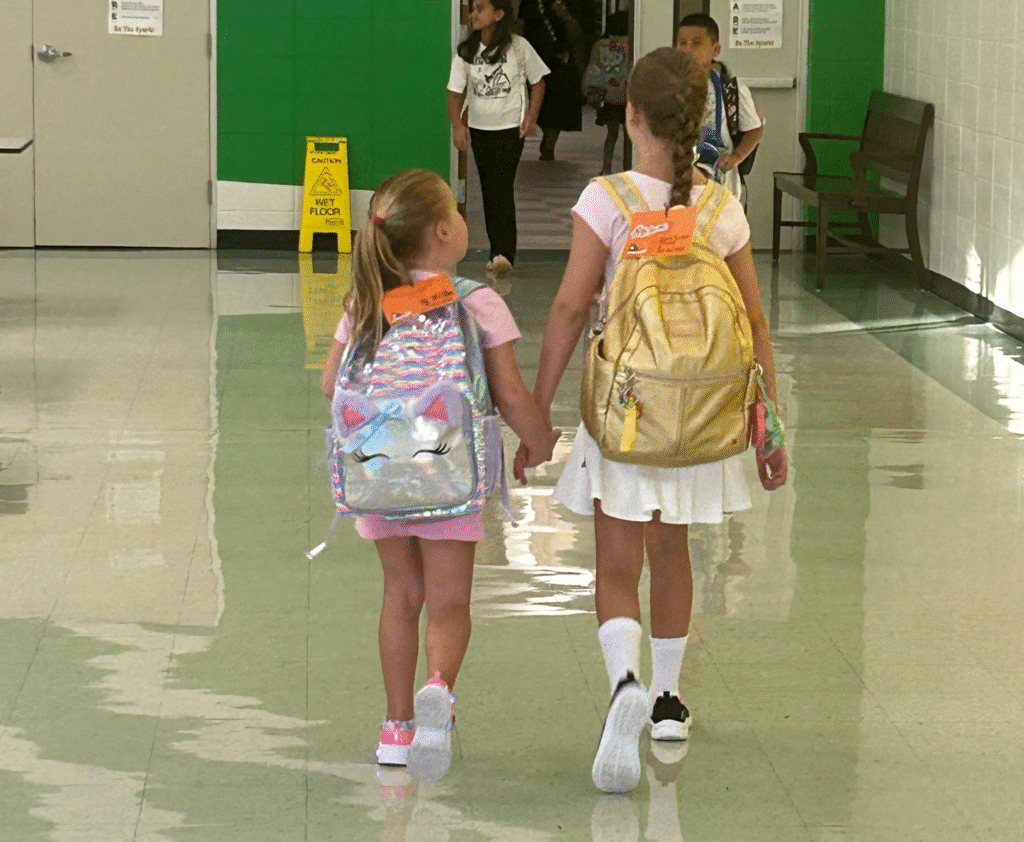 Sugar Mill Elementary, sisters holding hands, walking down hallway