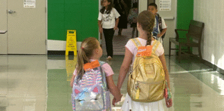 Sugar Mill Elementary, sisters holding hands, walking down hallway