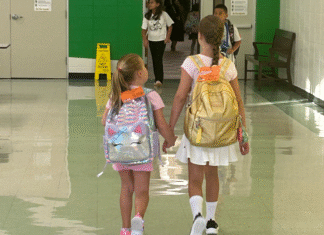Sugar Mill Elementary, sisters holding hands, walking down hallway