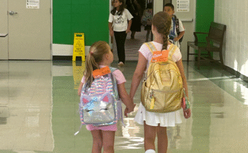 Sugar Mill Elementary, sisters holding hands, walking down hallway