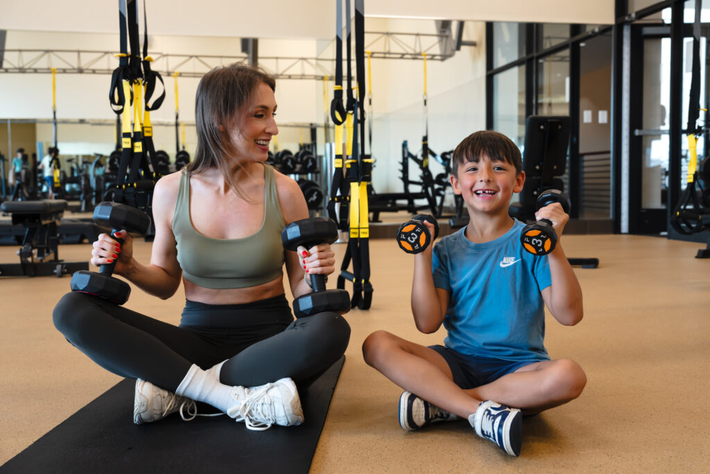 mom and child sit on floor lifting weights