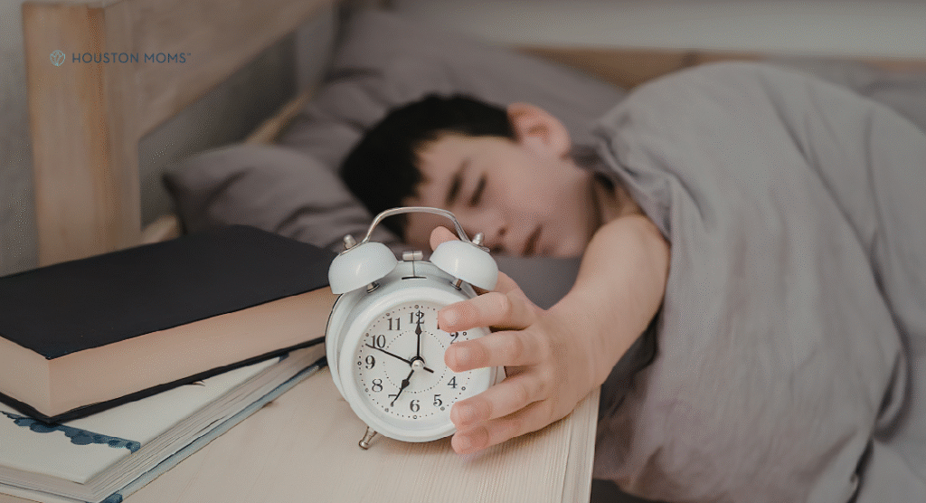 child in bed reaching for alarm clock