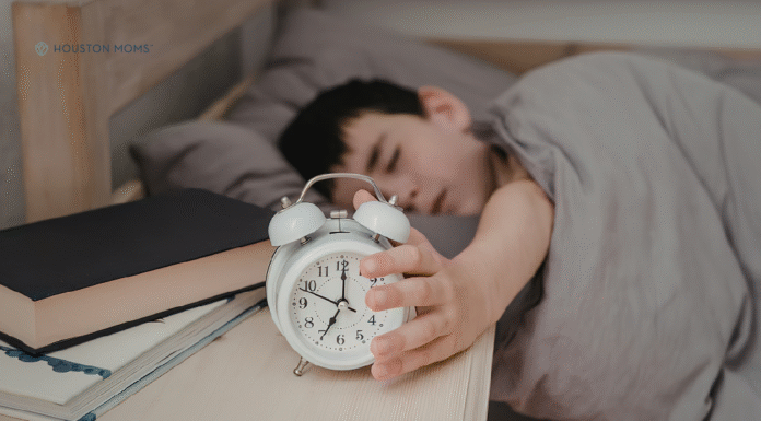 How to Help your Kids Adjust to Daylight Saving Time child in bed reaching for alarm clock