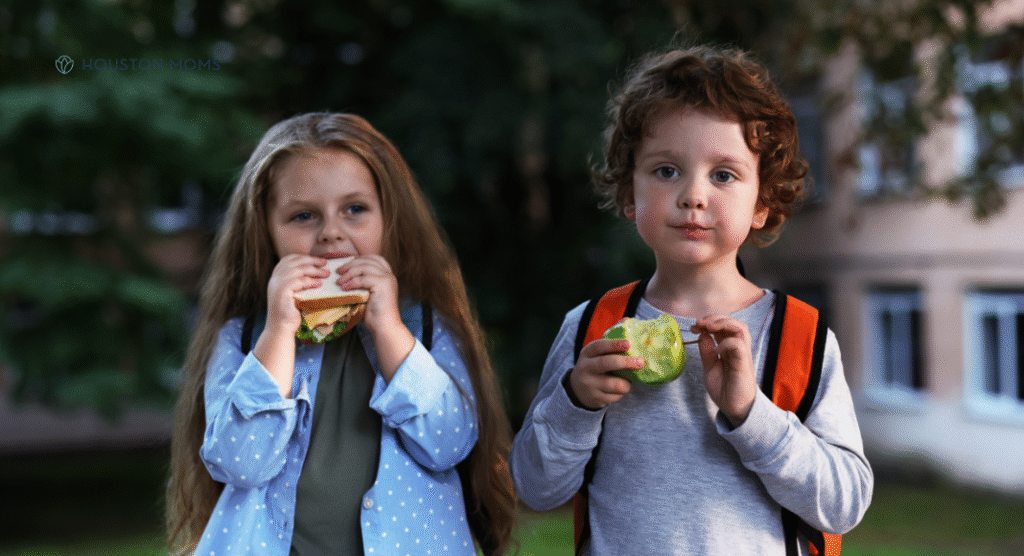 girl eating sandwich and boy eating an apple