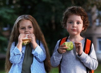 girl eating sandwich and boy eating an apple