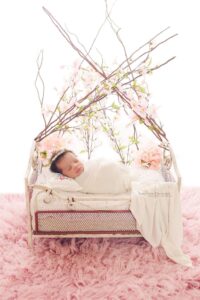 newborn in bed with flowers and sticks over her head
