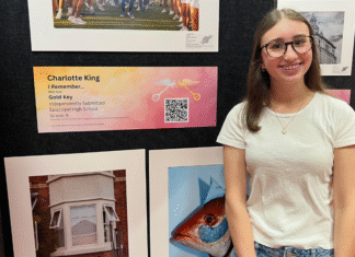girl standing in front of paintings and a plaque and QR code