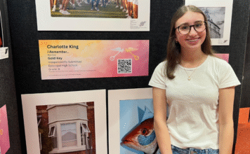 Raising Readers and Writers in a Digital World girl standing in front of paintings and a plaque and QR code