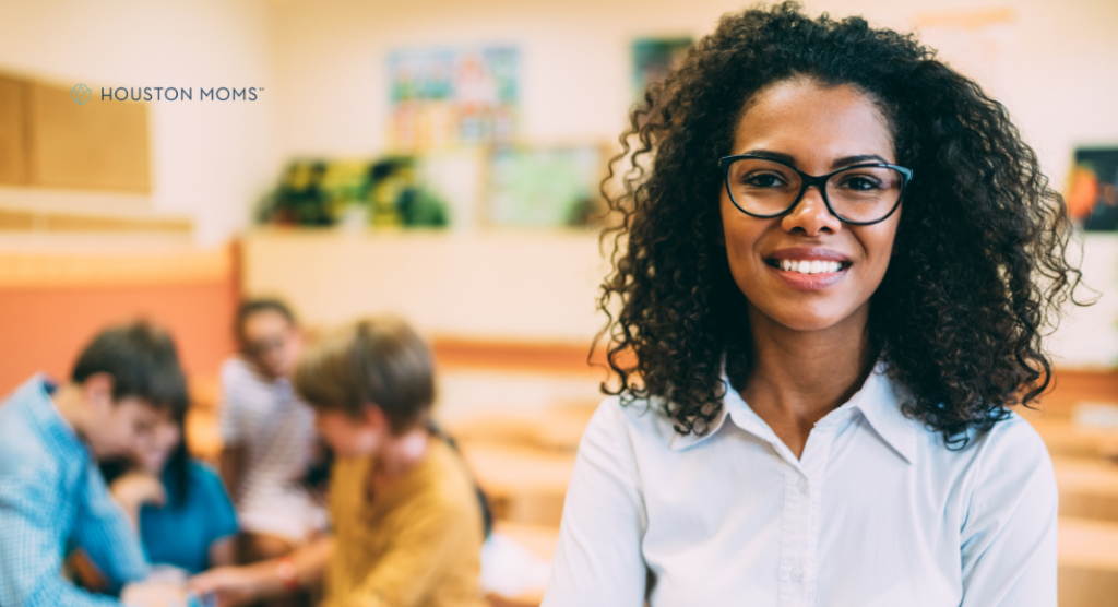 teacher stands in front of students who are seated and working