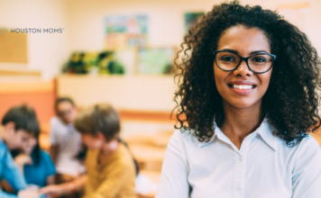 teacher stands in front of students who are seated and working