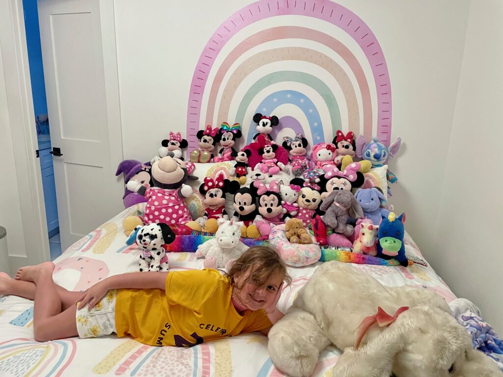 girl lays on bed with lots of stuffed animals 