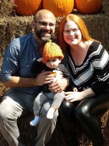 couple and baby pose at a pumpkin patch