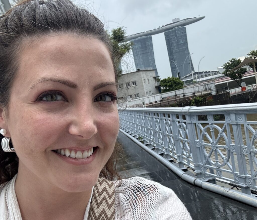 The author pictured ion a hop on, hop off bus in Singapore with Marina Bay Sands behind her