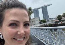 The author pictured ion a hop on, hop off bus in Singapore with Marina Bay Sands behind her
