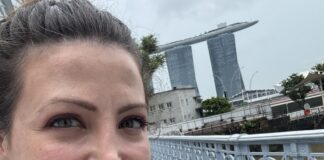 The author pictured ion a hop on, hop off bus in Singapore with Marina Bay Sands behind her