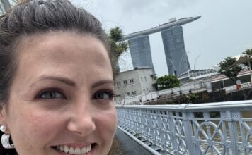 The author pictured ion a hop on, hop off bus in Singapore with Marina Bay Sands behind her