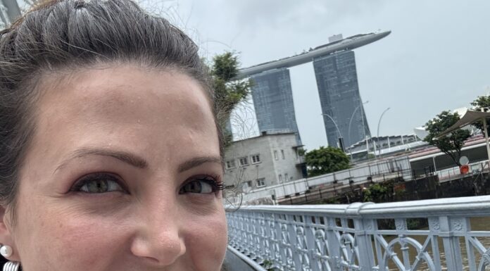 Around the World in 8 Days (And Other Things I Never Thought I’d Do) The author pictured ion a hop on, hop off bus in Singapore with Marina Bay Sands behind her