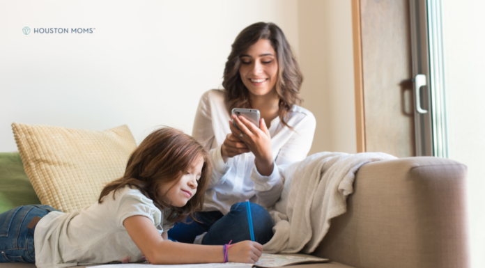 Momeaze: An App that Manages the Mental Load of Motherhood Mom sitting on couch looking at her phone while child draws next to her