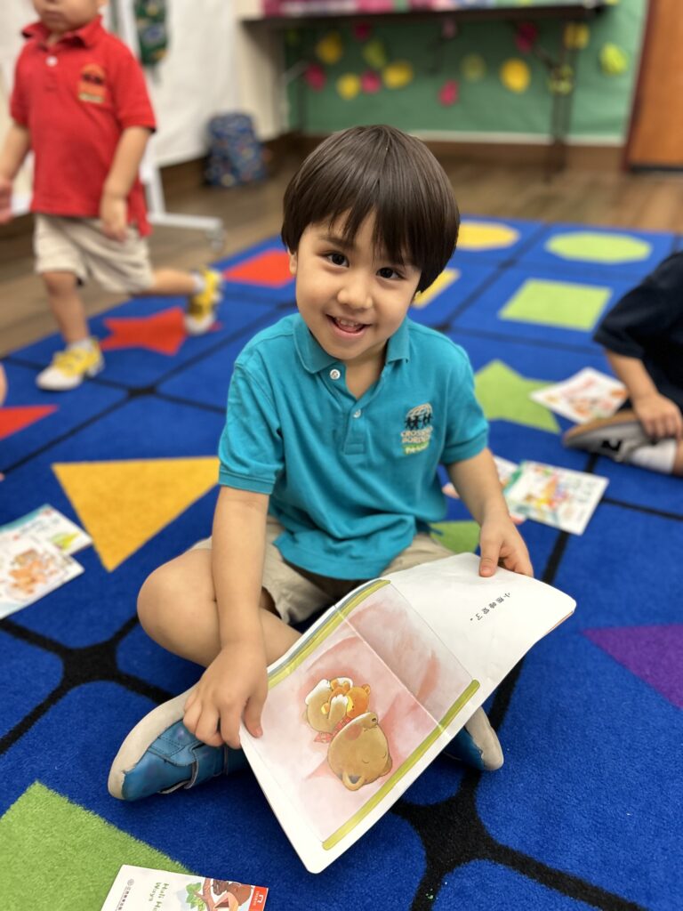 A preschool child sitting on floor looking at a book