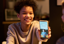 Stock image of teen showing parents a meme at dinner