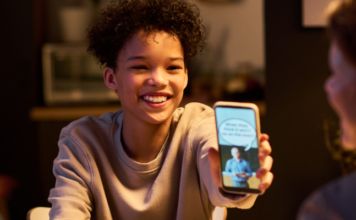 Stock image of teen showing parents a meme at dinner
